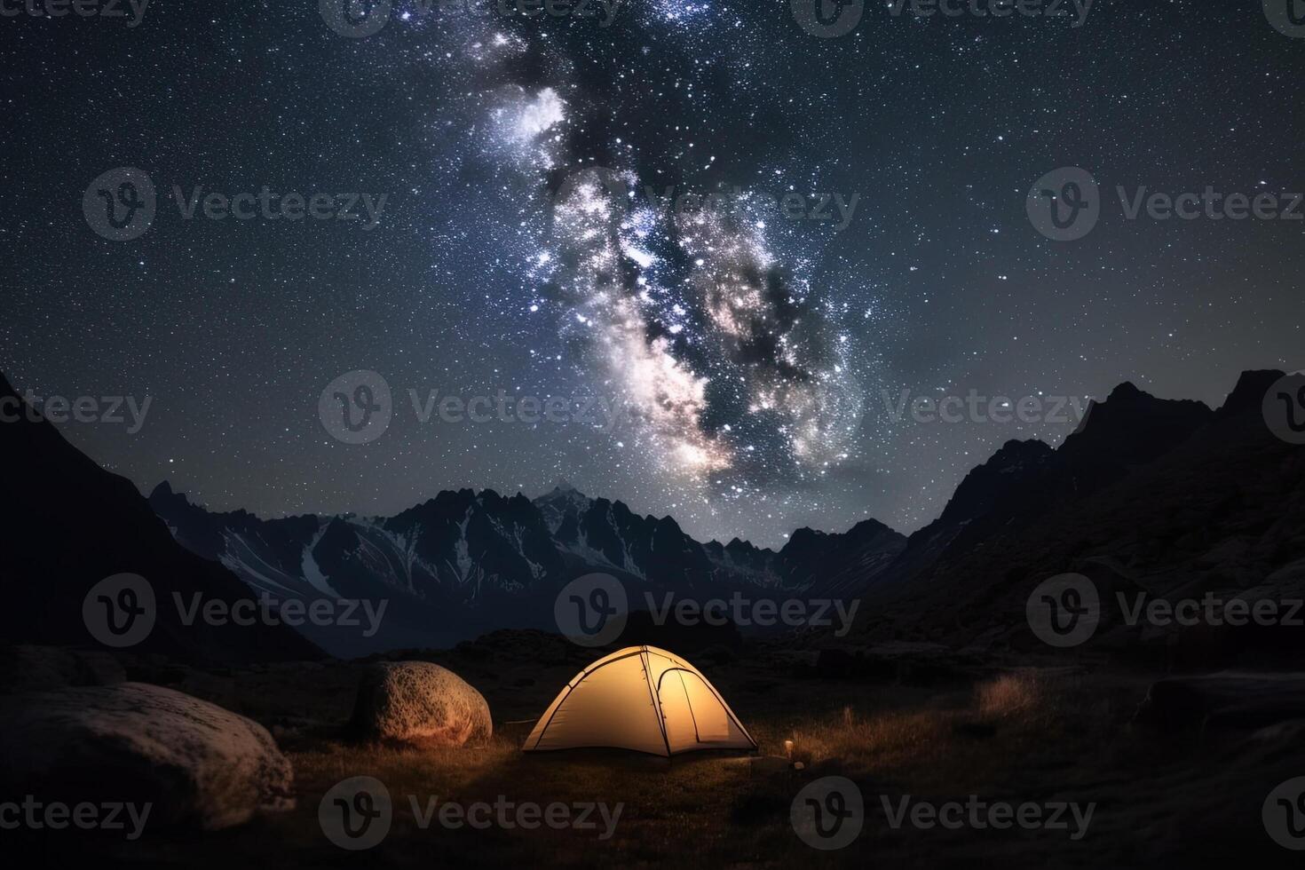 Camp with tent glowing from the inside at night in the mountains under the stars of the milky way. . photo