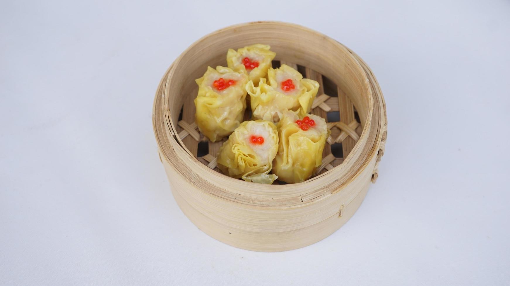 top view Chinese steamed dumplings in bamboo basket on white background photo