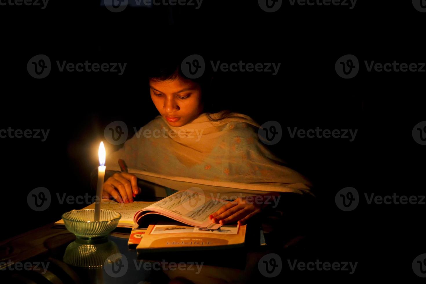 A young girl studying at home with candlelight after electricity load shedding at Dhaka City. photo