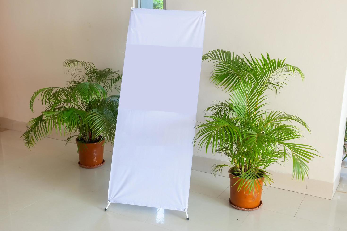A white blank design display X-Stand on an indoor wall side. A Blank Banner Design display X-Stand Mockup. Template Mock up for your content and design. photo