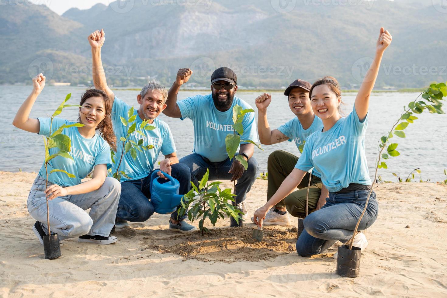 Group of volunteer smiling friends making fist pump gesture over beach. Protection Of Environment And Nature, Ecology Concept. photo