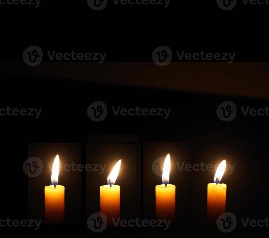 Yellow Candles Burning in the Dark with lights glow. The burning candle's flame in the dark background. a symbol of the Christian faith. photo