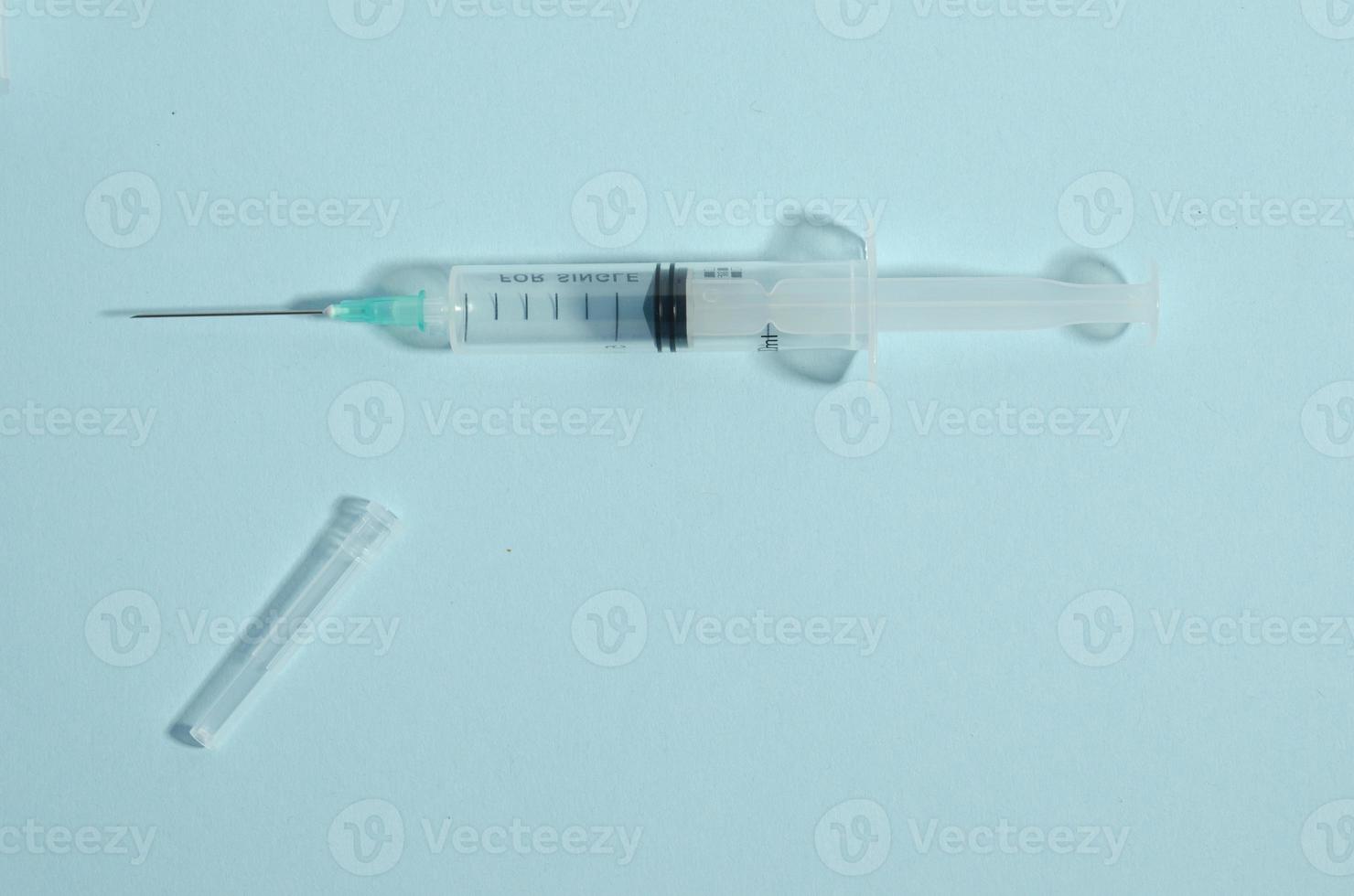 Syringe on a blue background. Syringe with an open cap. Needle. Single medicine object on the blue background with copy space. photo