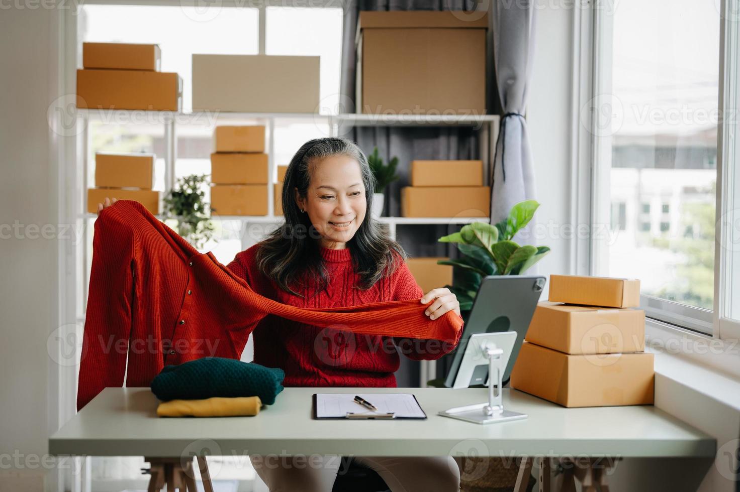 Moda blogger concepto, mayor asiático mujer de venta ropa en vídeo streaming.startup pequeño negocio pequeño, utilizando teléfono inteligente o tableta tomando recibir y comprobación foto