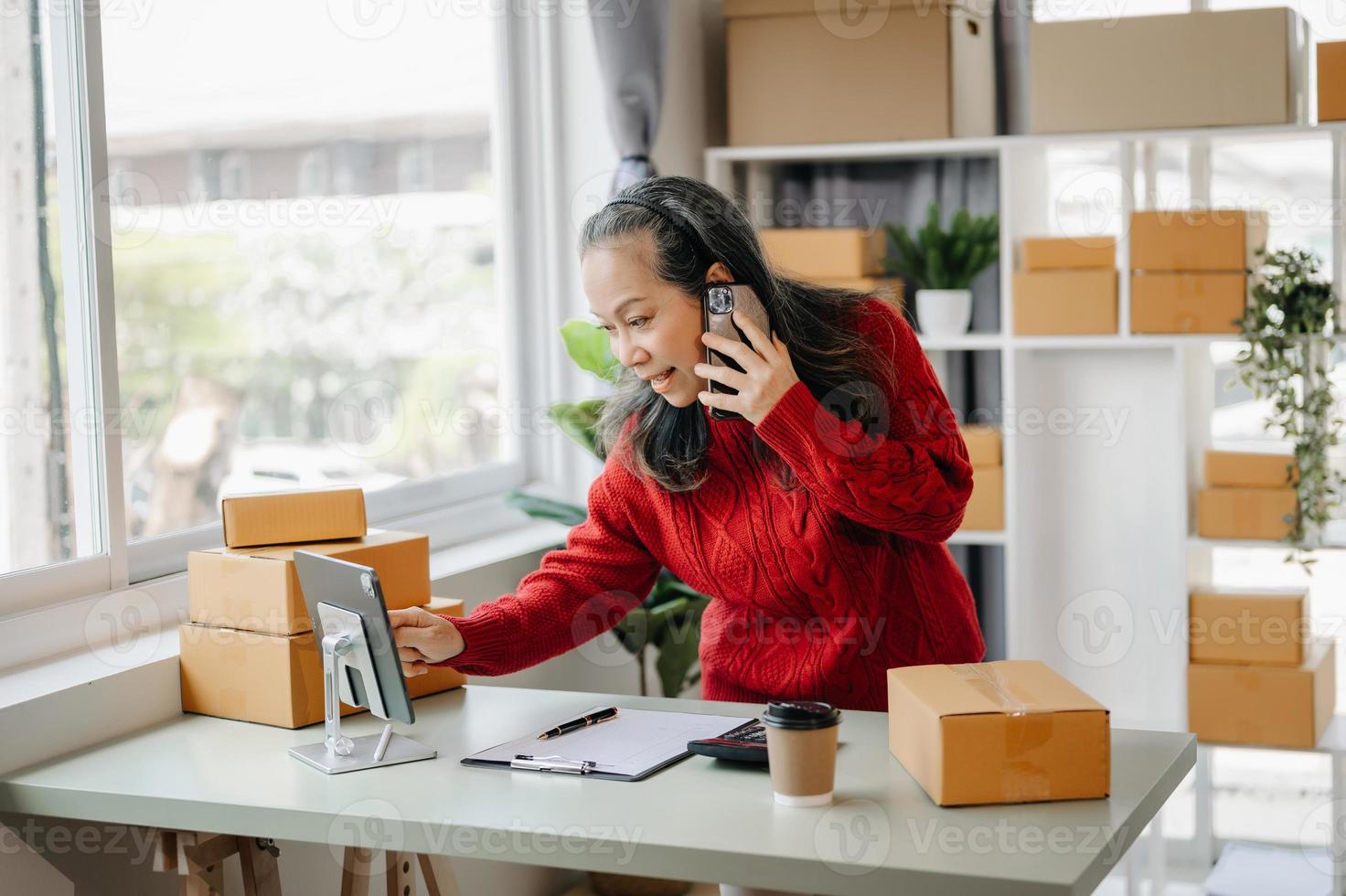 Senior business owner woman prepare parcel box and standing check online orders for deliver to customer on tablet, laptop Shopping Online concept. at home office photo