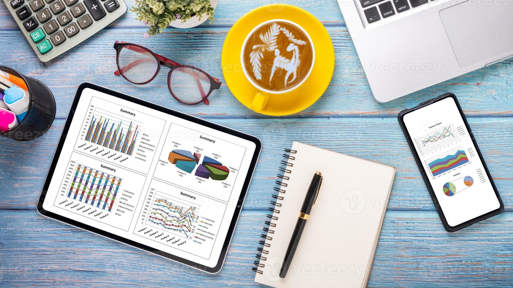 Tablet and smartphone with charts and reports on wooden desk workplace. Top view flat lay photo