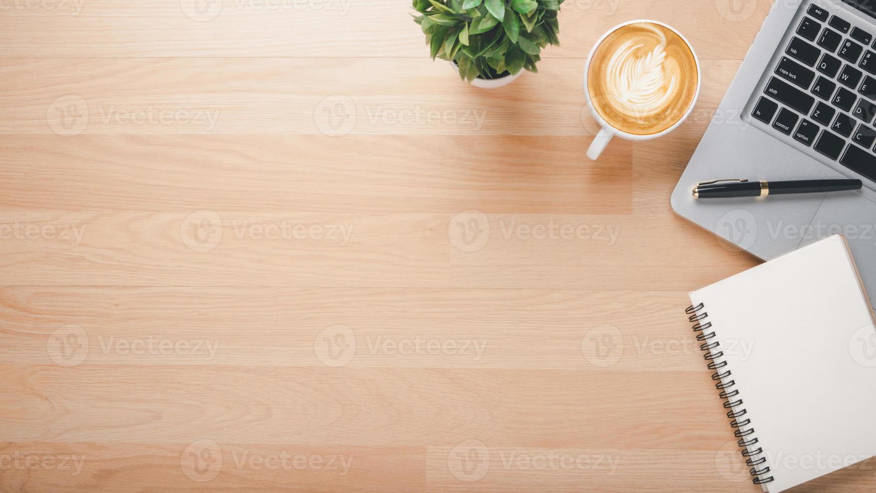 Wooden desk workplace with laptop computer, notebook, pen and cup of coffee, Top view flat lay with copy space. photo