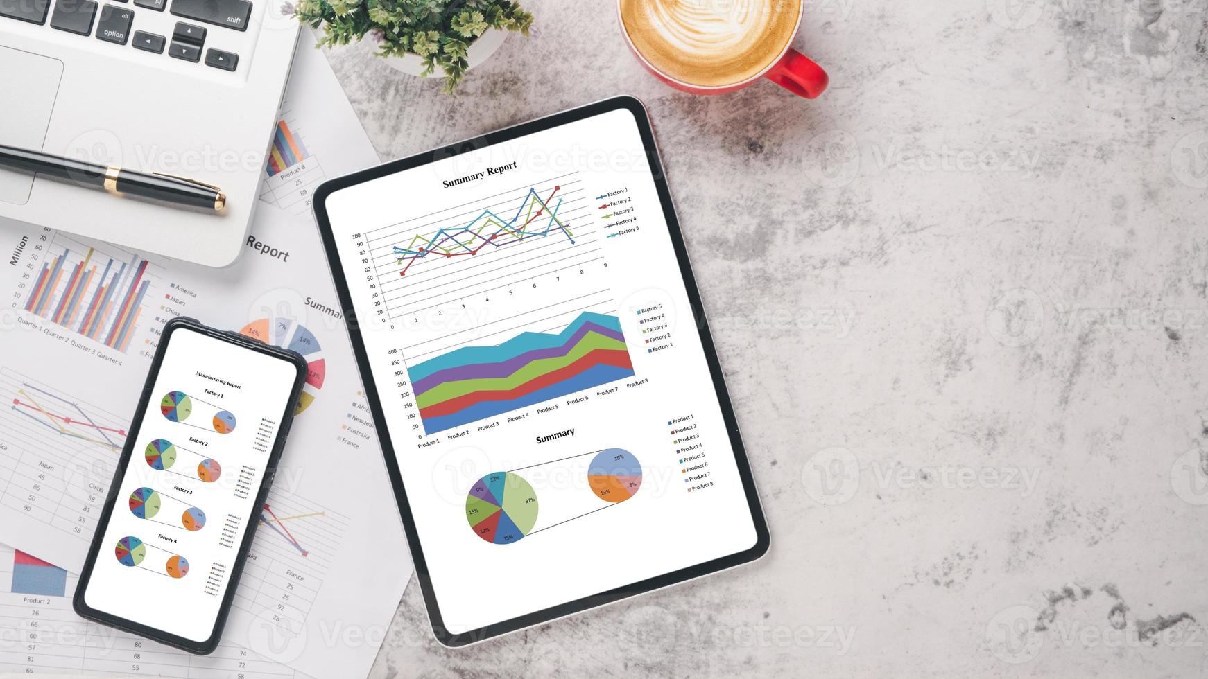 Tablet and smart phone with charts and reports, calculator, pen, notebook and coffee on office desk workplace. Top view flat lay with copy space. photo