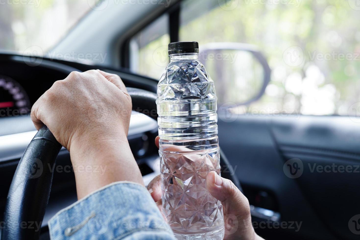 Asian woman driver hold cold water for drink in car, dangerous and risk