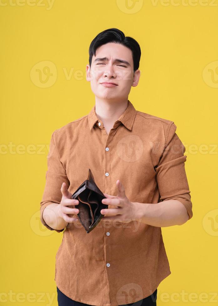 Young Asian man with empty wallet on background photo
