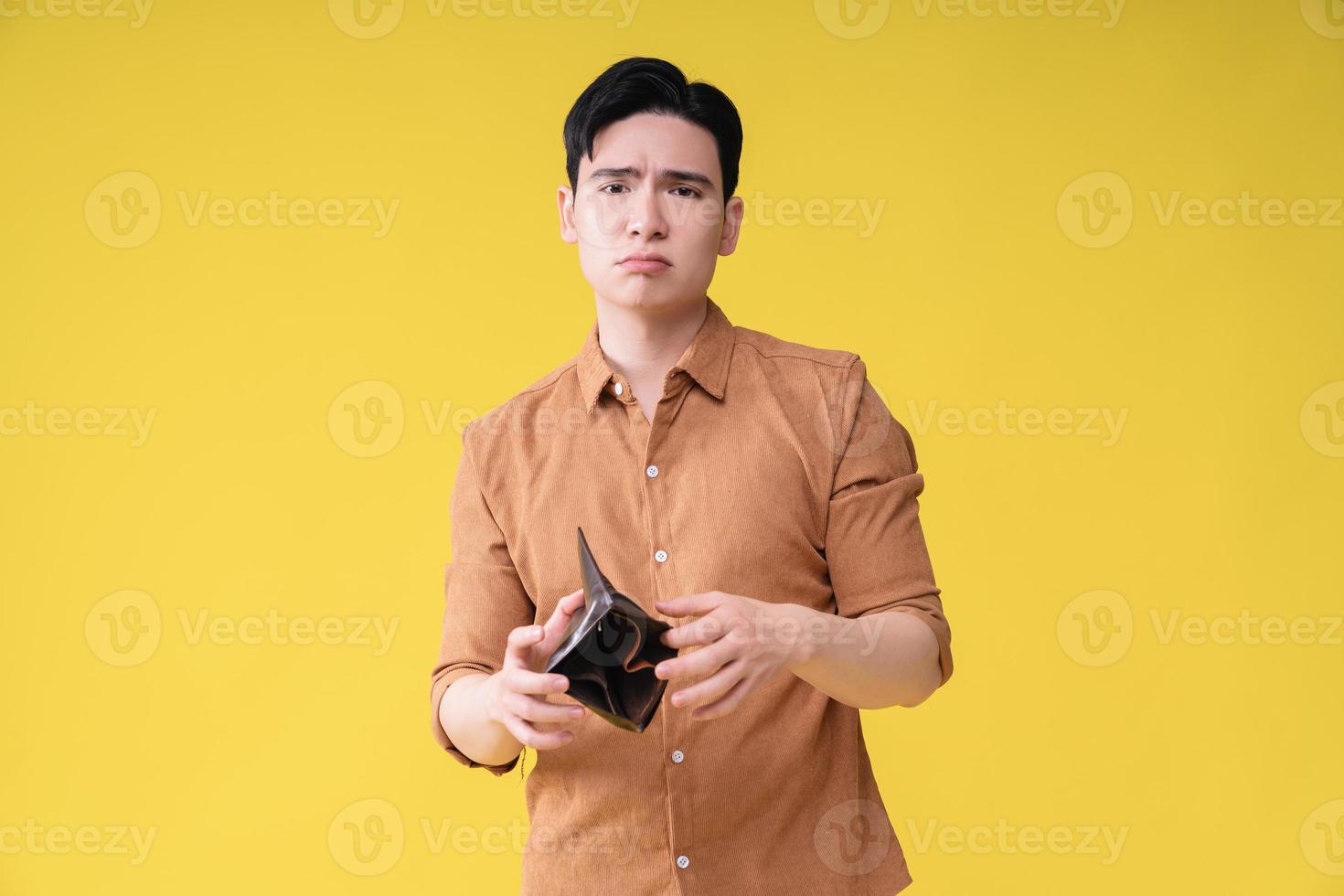 Young Asian man with empty wallet on background photo