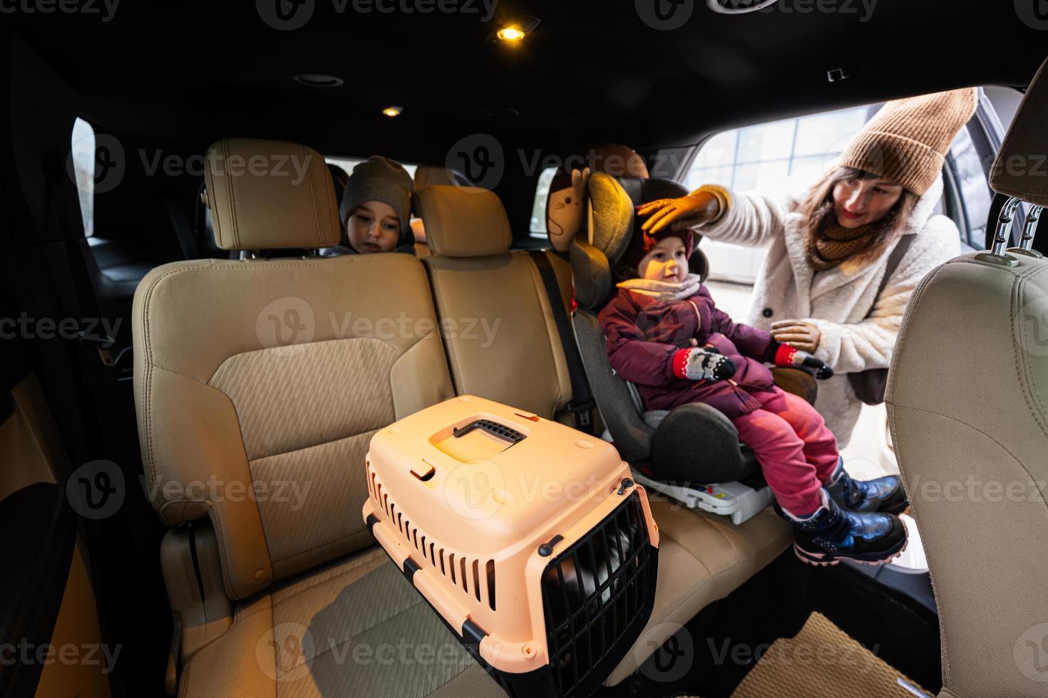 Mother and daughters with cat travel plastic cage carriage in car. photo