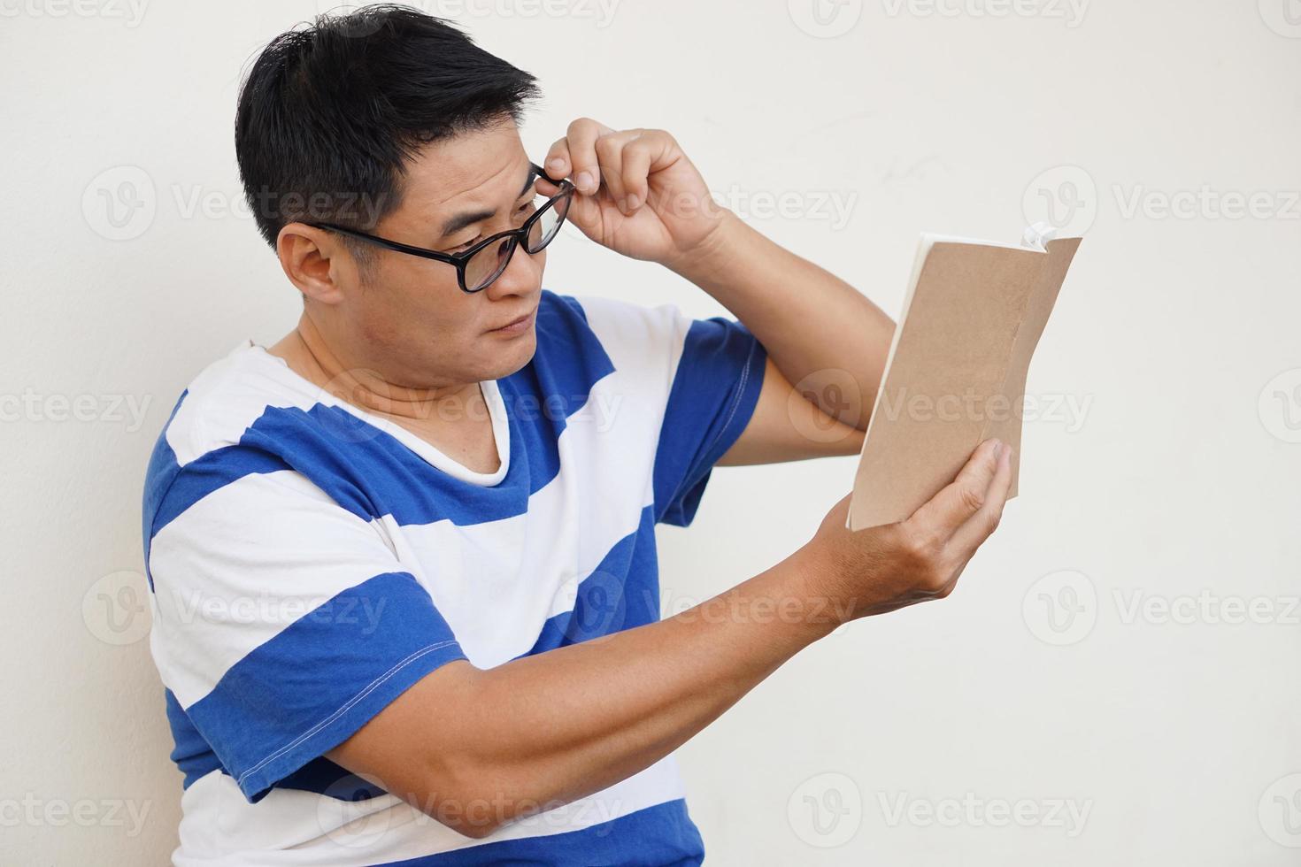 Asian middle aged man wears eyeglasses is reading book. concept , Eyesight problem. Optometry. Glasses with convex or concave lenses. Myopia.Eye disease photo