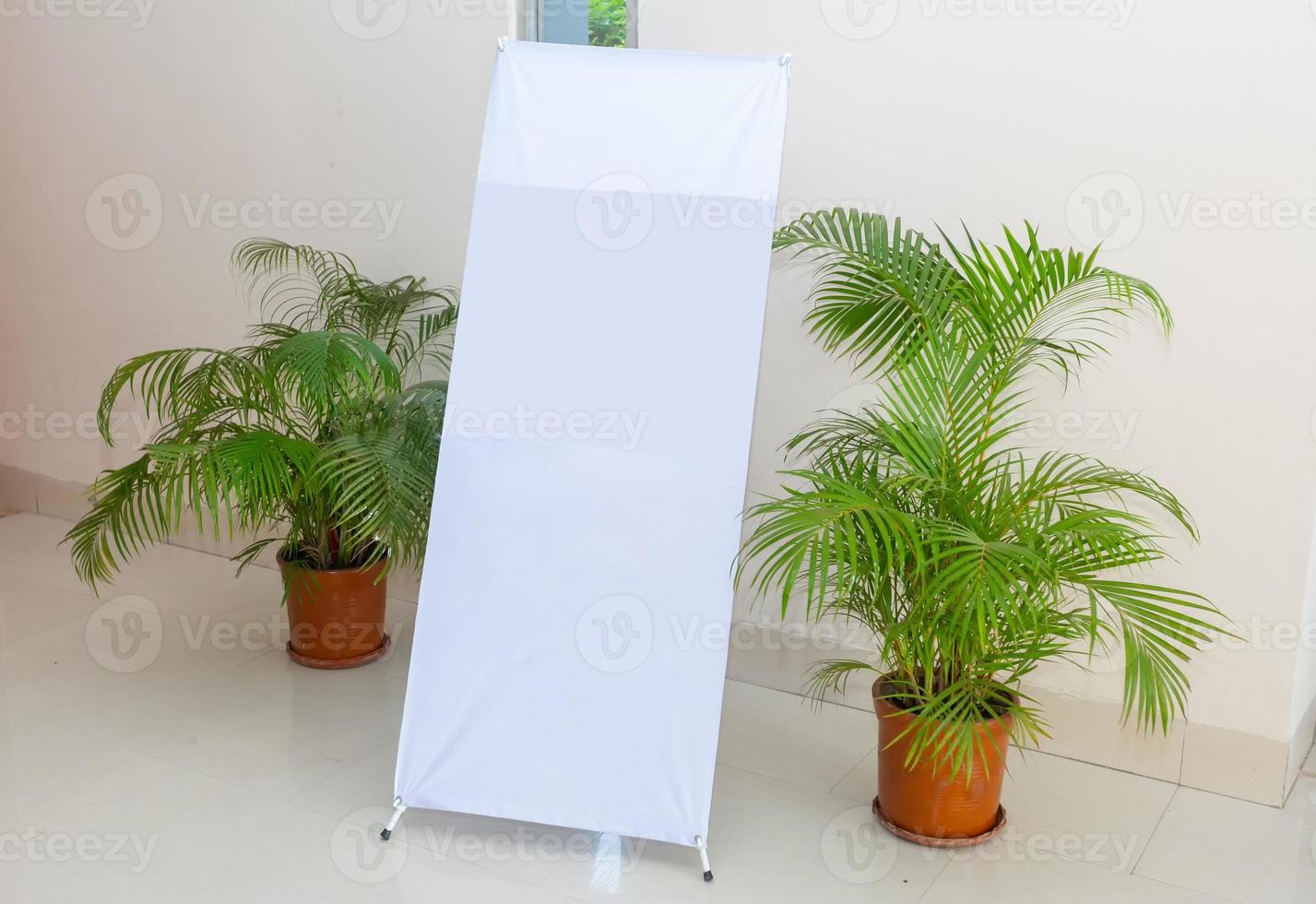 A white blank design display X-Stand on an indoor wall side. A Blank Banner Design display X-Stand Mockup. Template Mock up for your content and design. photo