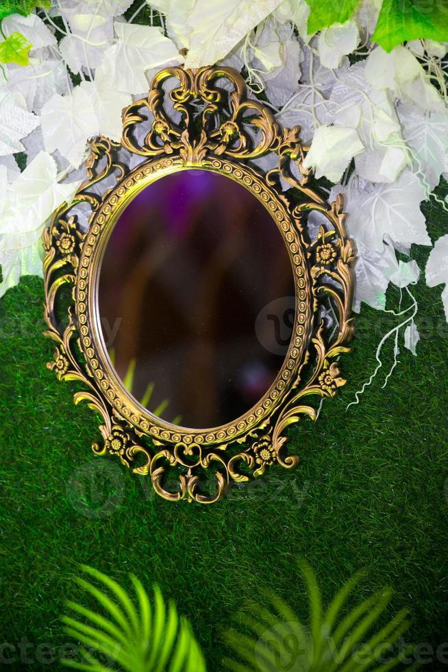 Green artificial grass based wedding stage with handcrafted oval-shaped vanity wall mirror decoration background. Plastic artificial flower. Wedding decoration. photo