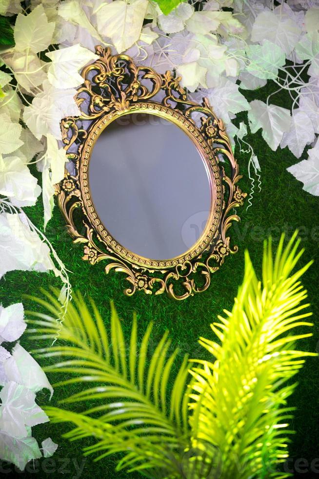 Green artificial grass based wedding stage with handcrafted oval-shaped vanity wall mirror decoration background. Plastic artificial flower. Wedding decoration. photo