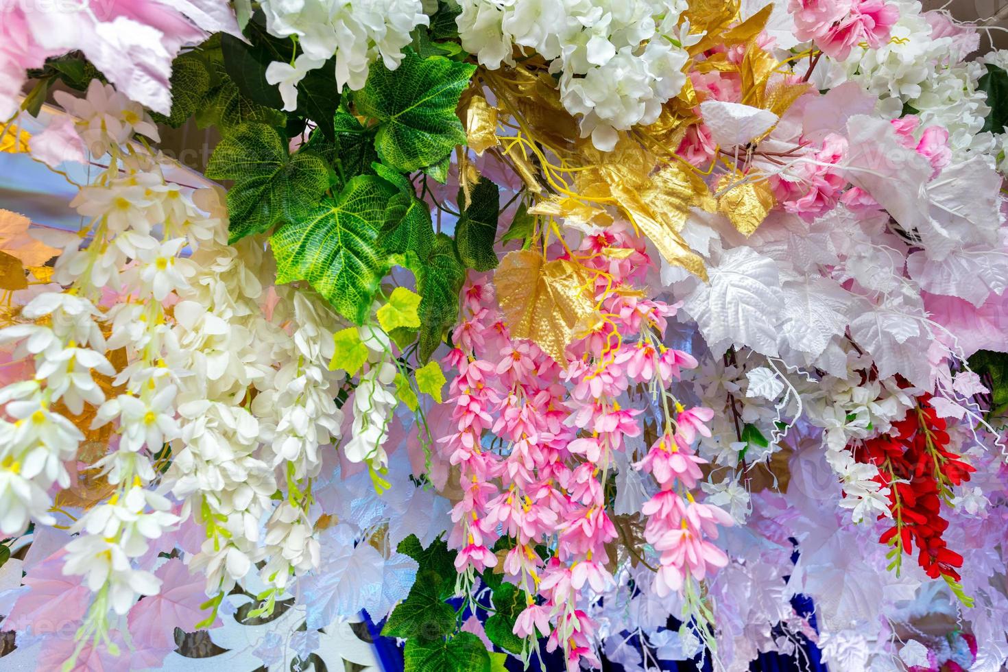 Colorful artificial paper flowers hanging on a stage. wedding decoration. Plastic colorful