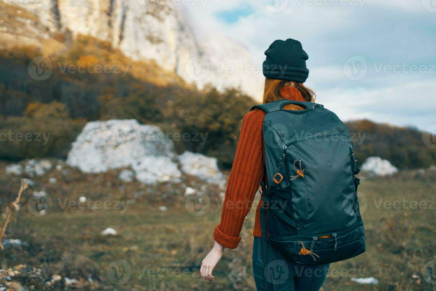 woman tourist in a hat with a backpack climbs the mountains in nature back view photo