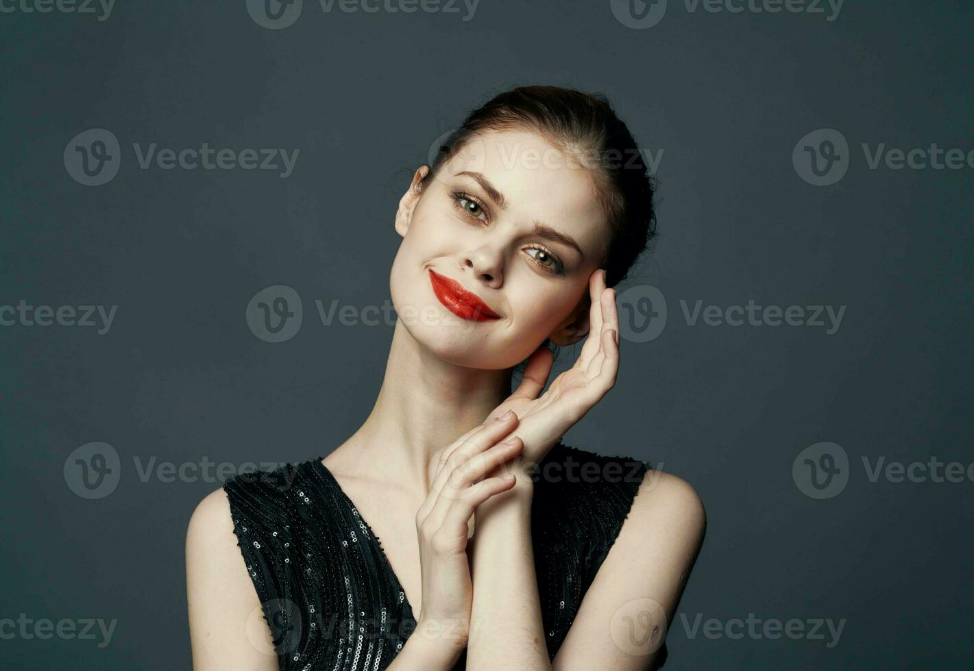 Charming lady in a black dress gestures with her hands on a gray background Copy Space photo