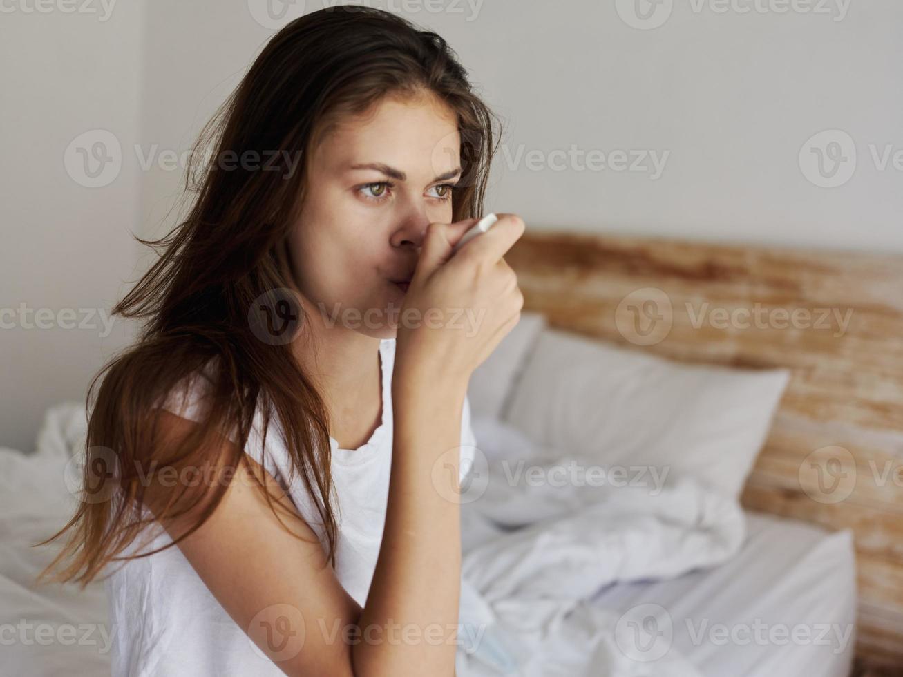 woman in white t-shirt checks her mouth temperature photo