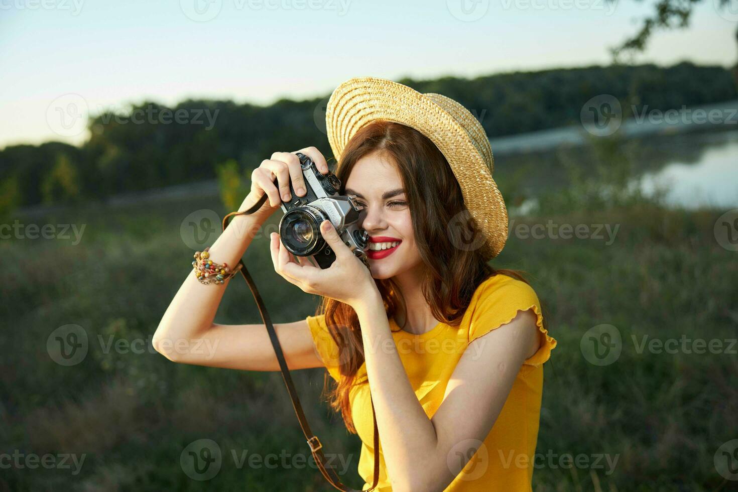 mujer fotógrafo en sombrero mirando dentro el cámara lente sonrisa naturaleza pasatiempo foto