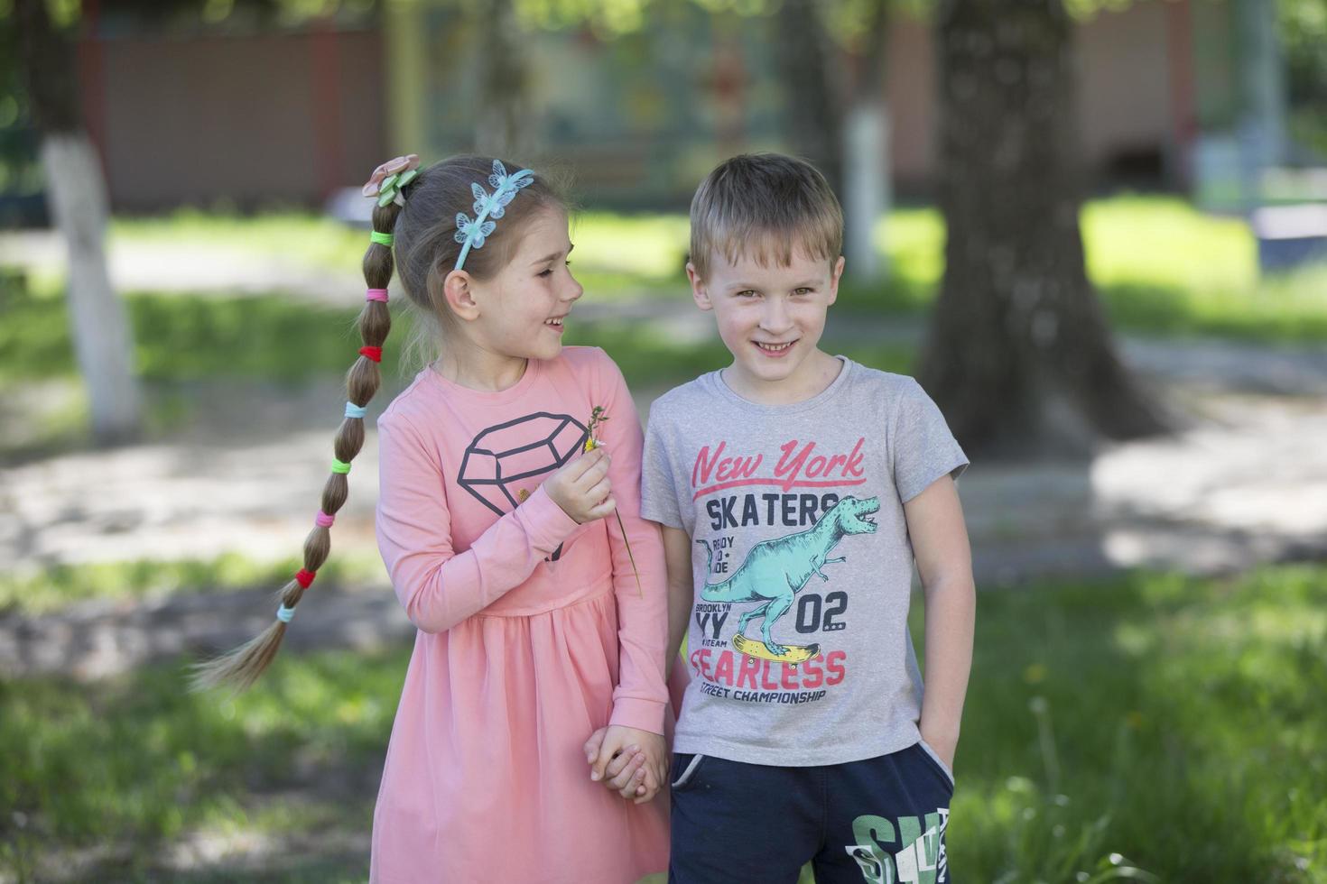 Cheerful children from kindergarten on a summer walk. Six year old boy and girl play in the garden. photo