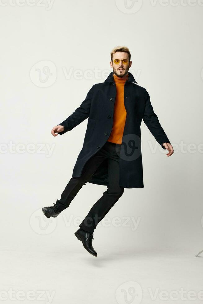 happy man in a coat and trousers jumped up on a light background photo