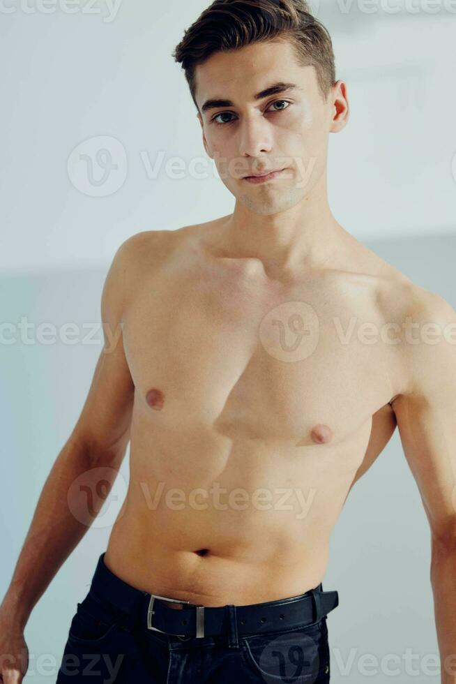 A man in dark pants and with a naked torso on a light background photo