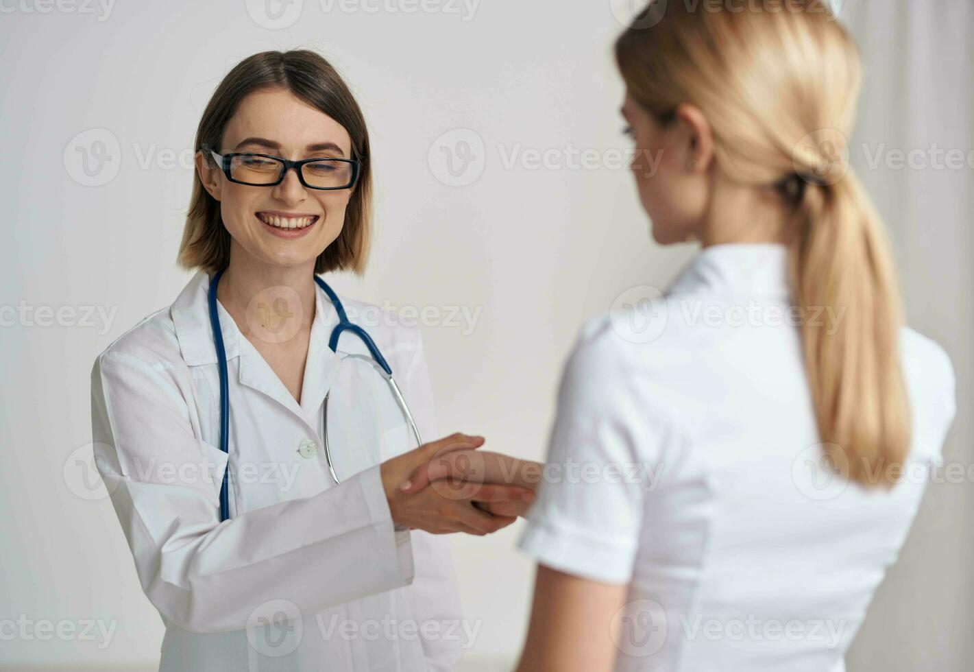 doctor and patient shaking hands on a light background stethoscope around the neck photo