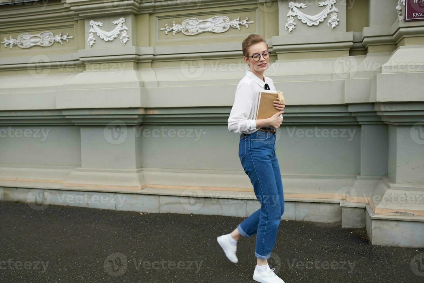 student with glasses walking around the city with a book communication photo