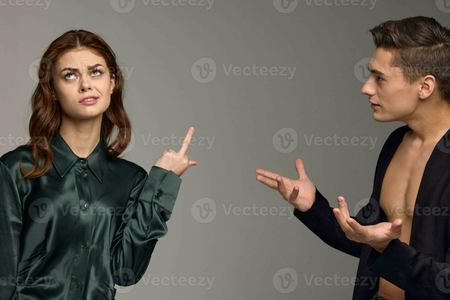 A woman shows her thumb up and a puzzled man gestures with his hands on a gray background photo