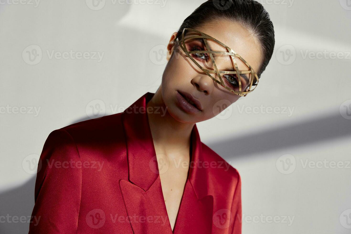 accesorios en el cara de un de moda mujer en un rojo chaqueta en un ligero antecedentes recortado ver retrato foto