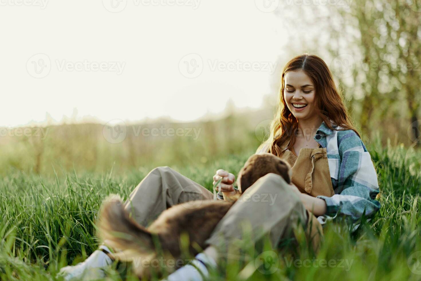 mujer juego con su perro en naturaleza sonriente y acostado en el verde césped en el parque, contento sano relación Entre amante y mascota foto