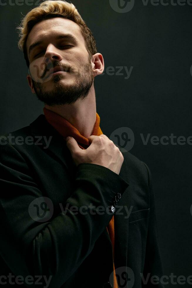 portrait of a guy in an orange sweater and coat on a dark background close-up cropped view photo