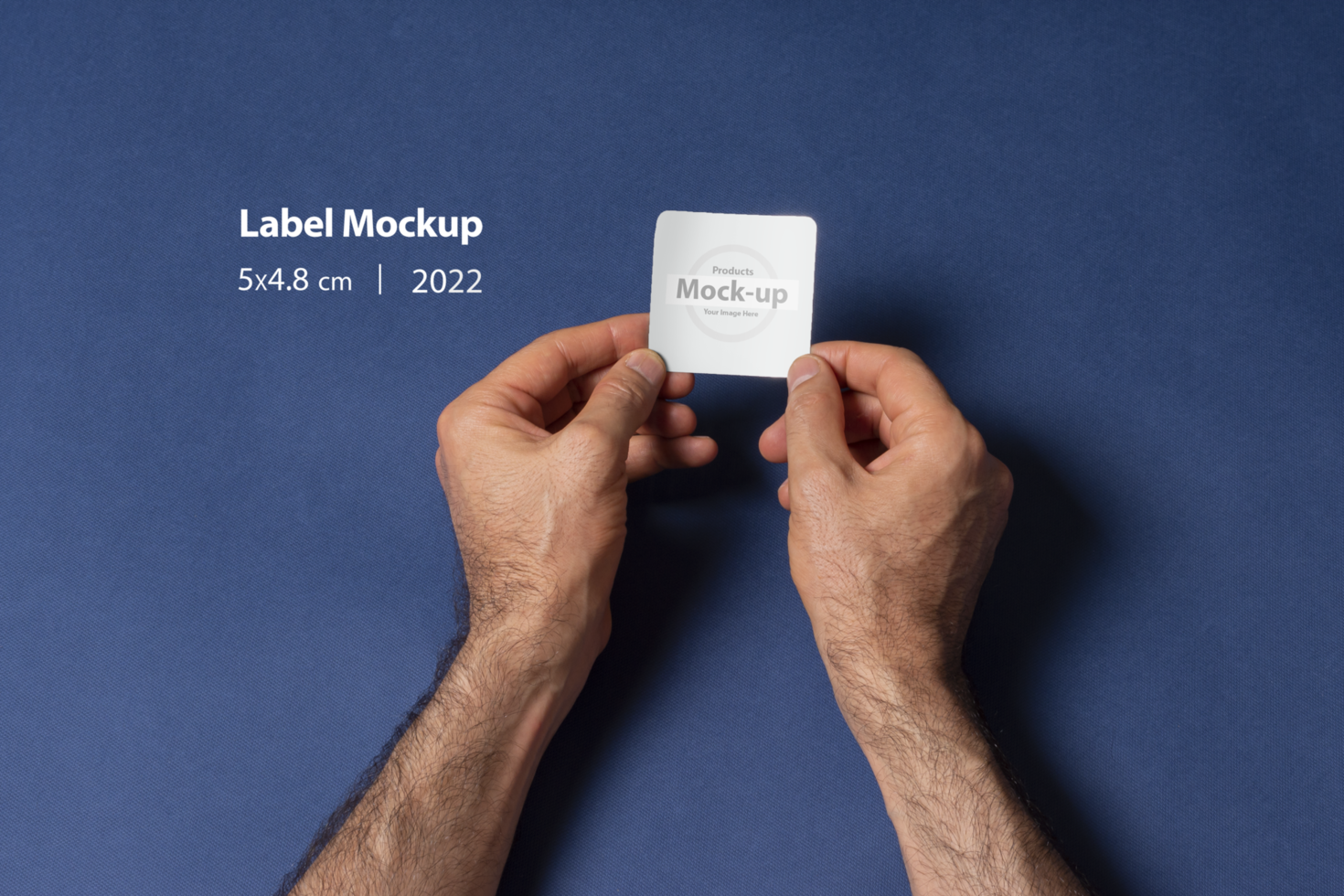 A man hands holding a small label in front of dark blue background psd