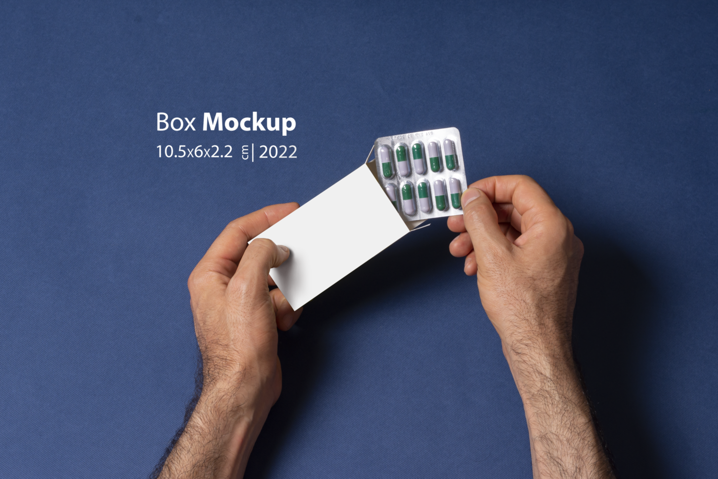 Male hand putting a capsule pills tablet in box in front of blue background psd