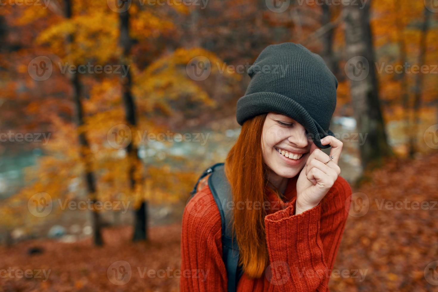 mujer en un sombrero y un suéter con un mochila en su espalda divertido otoño paisaje río foto