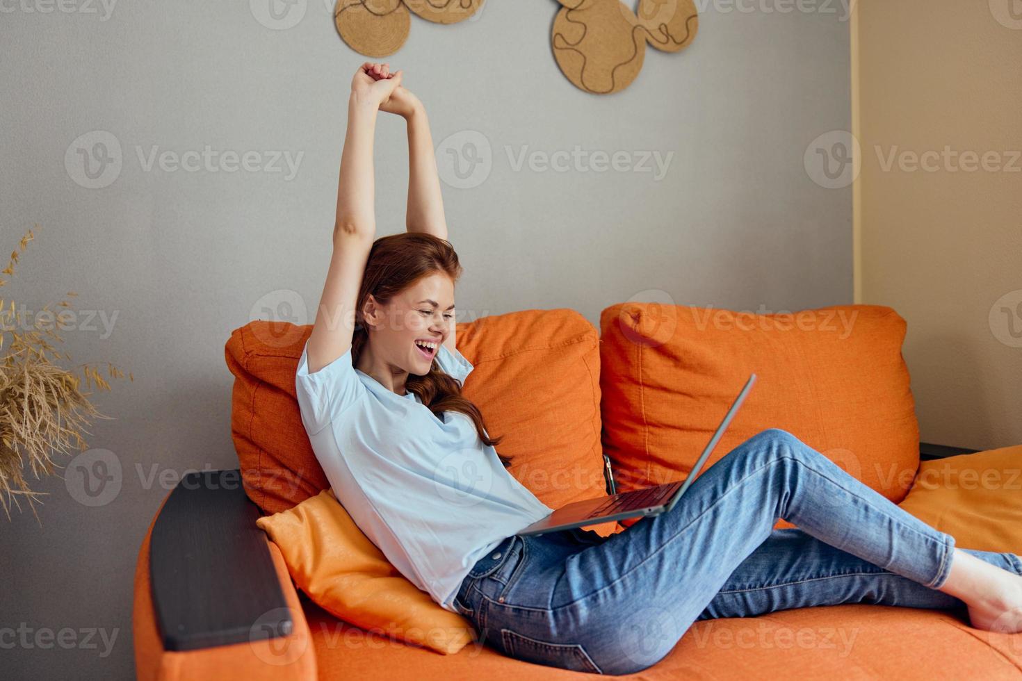 beautiful woman chatting on the orange couch with a laptop technologies photo