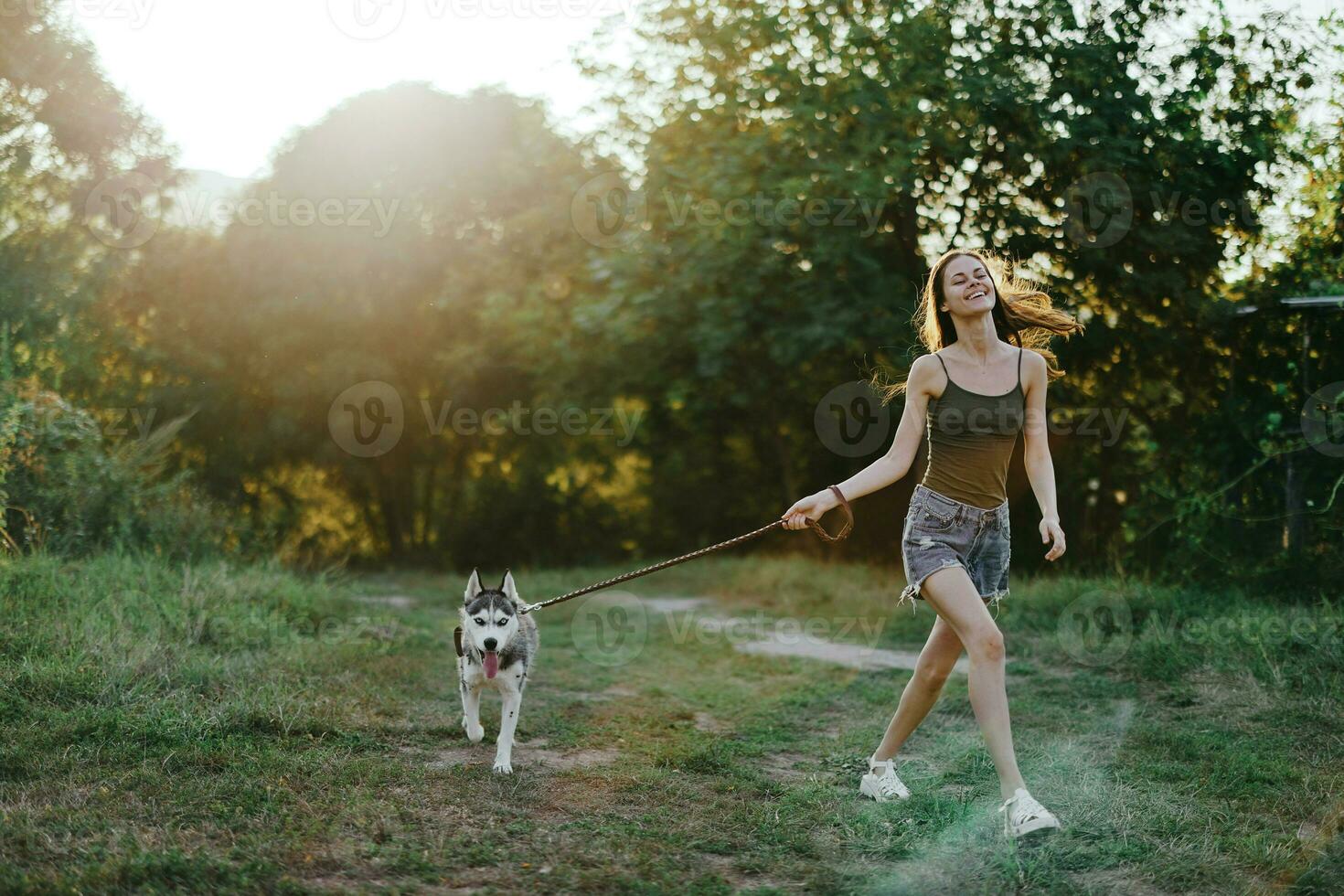 Woman and her husky dog happily running through the grass in nature in the park smile with teeth fall walk with pet, traveling with a dog friend photo