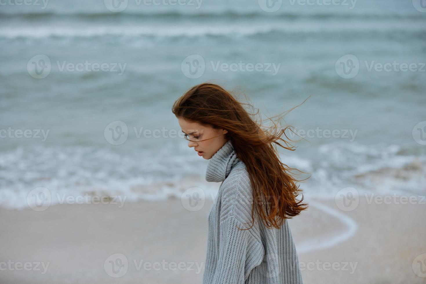 bonito mujer en un suéter volador pelo por el Oceano turismo inalterado foto