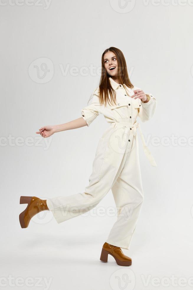 fashionable woman in jumpsuit and fashionable boots on a light background in full growth photo