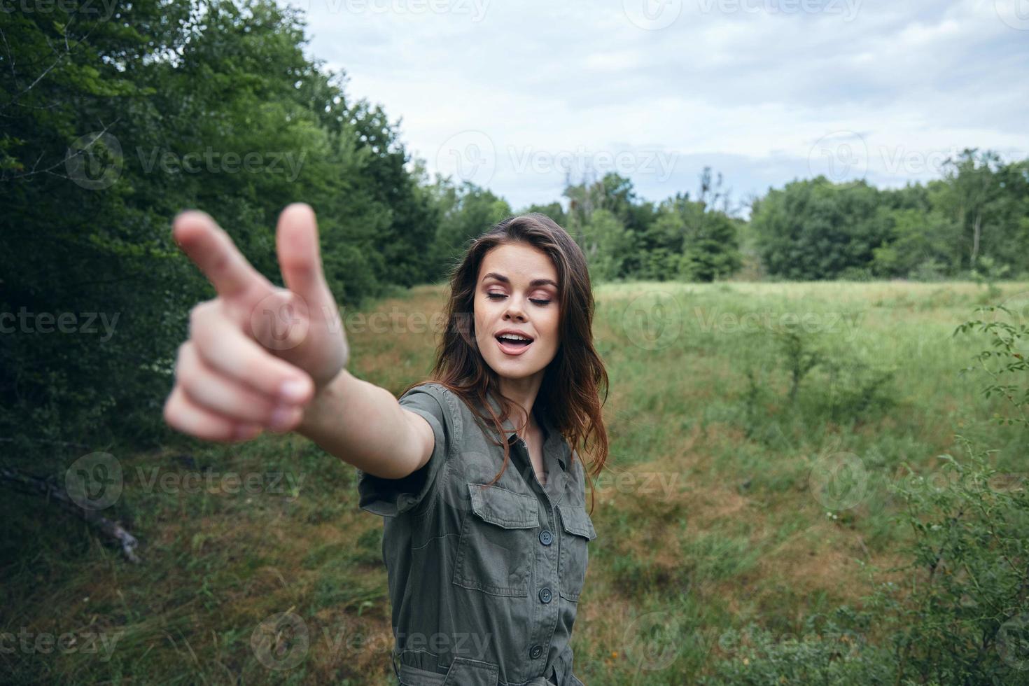 Woman portrait on nature Eyes closed, showing fresh air with a finger photo