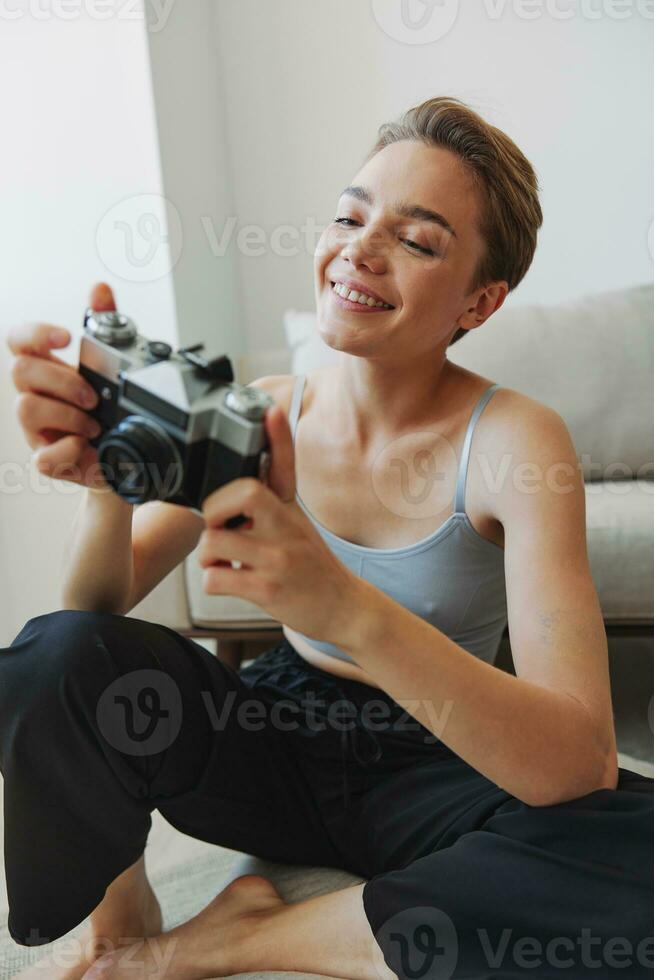 Happy smile woman holding an old camera and taking pictures of herself as a weekend photographer in home clothes with a short haircut hair without filters on a white background, free copy space photo
