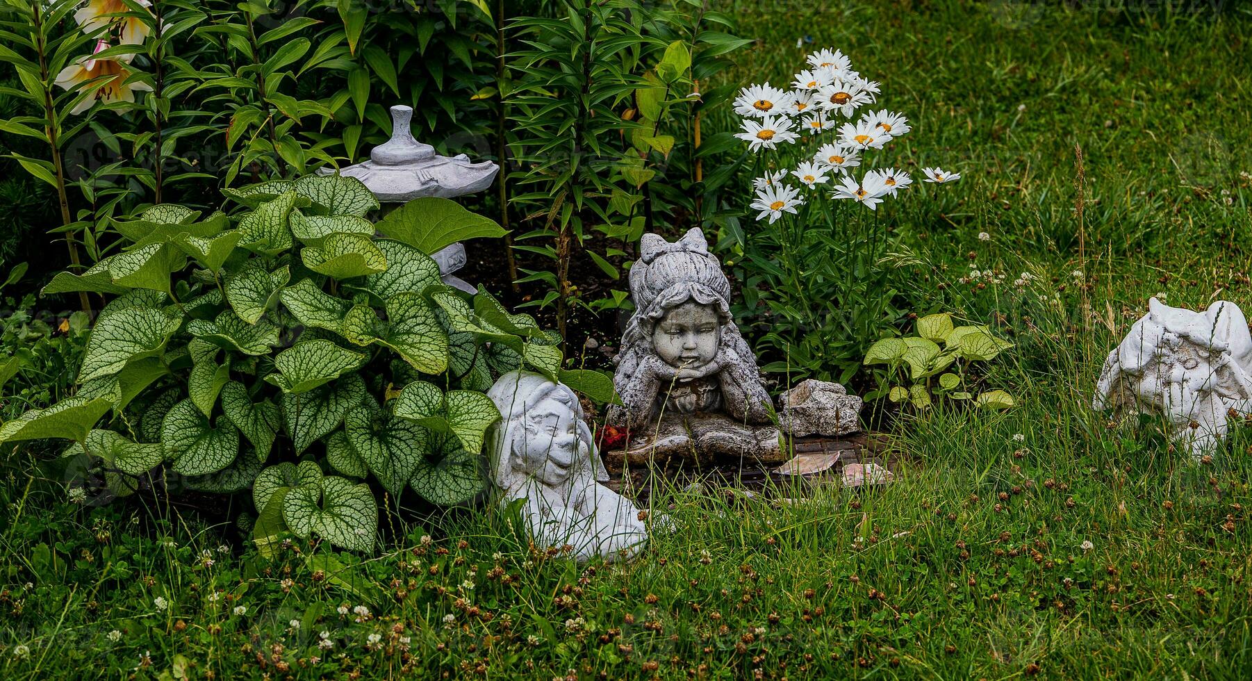 green garden with flowers and plaster figurine natural background photo