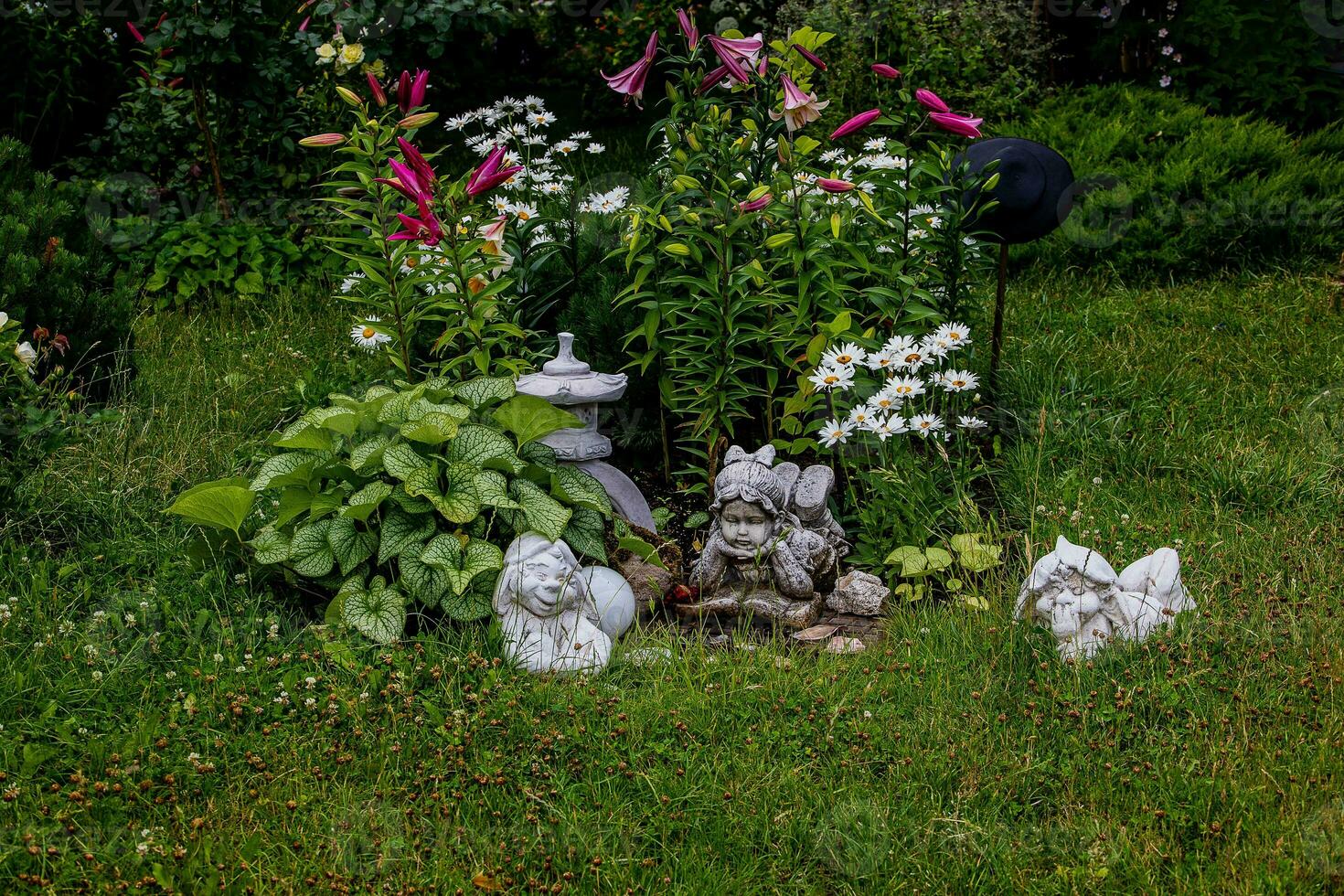 green garden with flowers and plaster figurine natural background photo