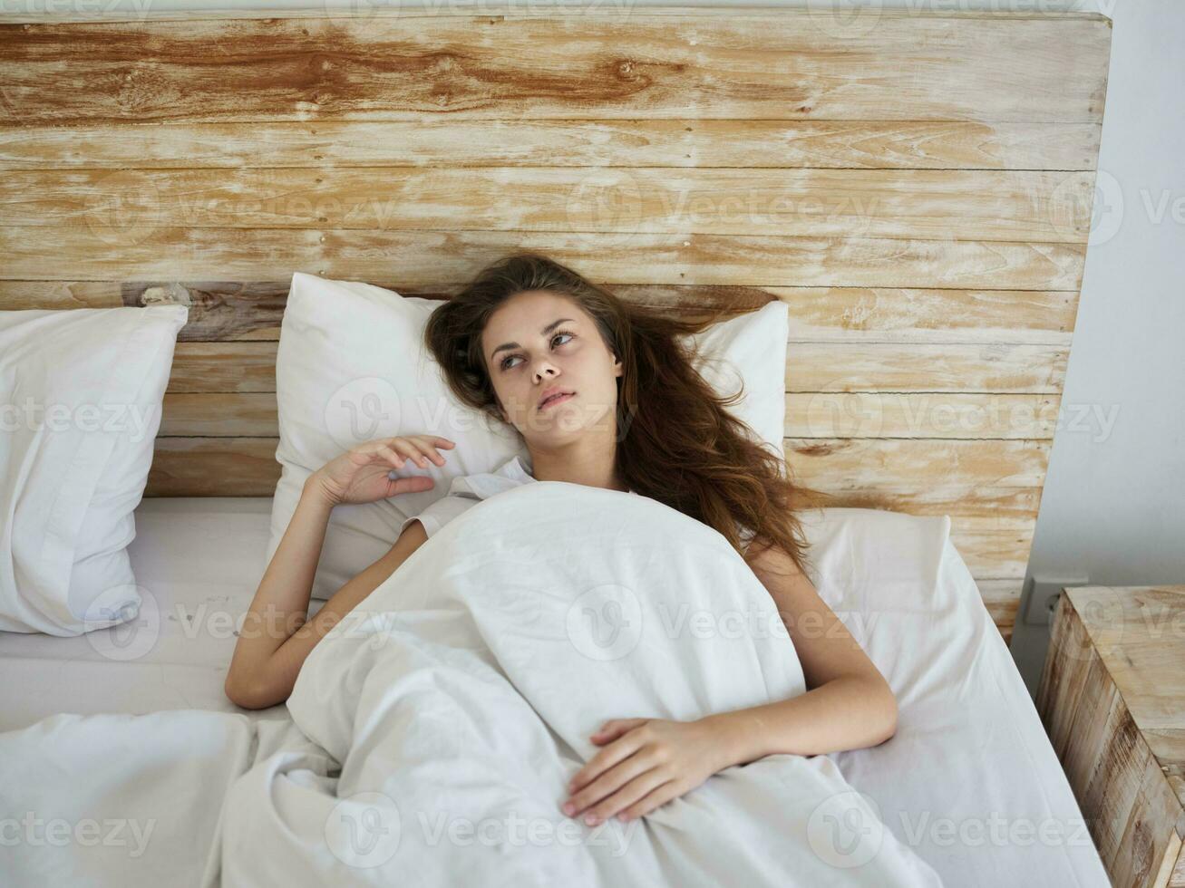 woman lies in bed under the blanket in the morning relaxation emotions photo