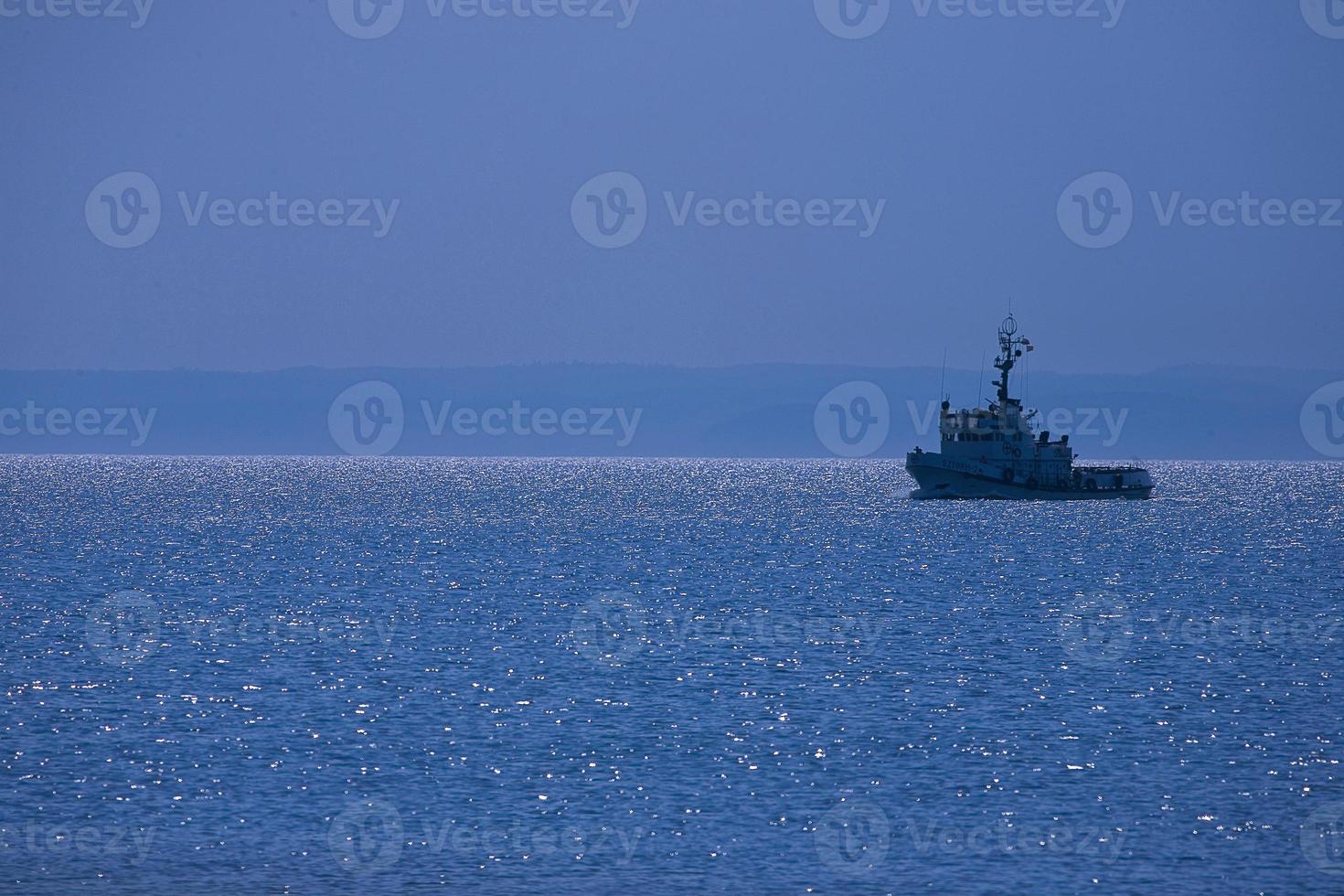 landscape a small ship sailing on the blue sea and cloudless sky photo