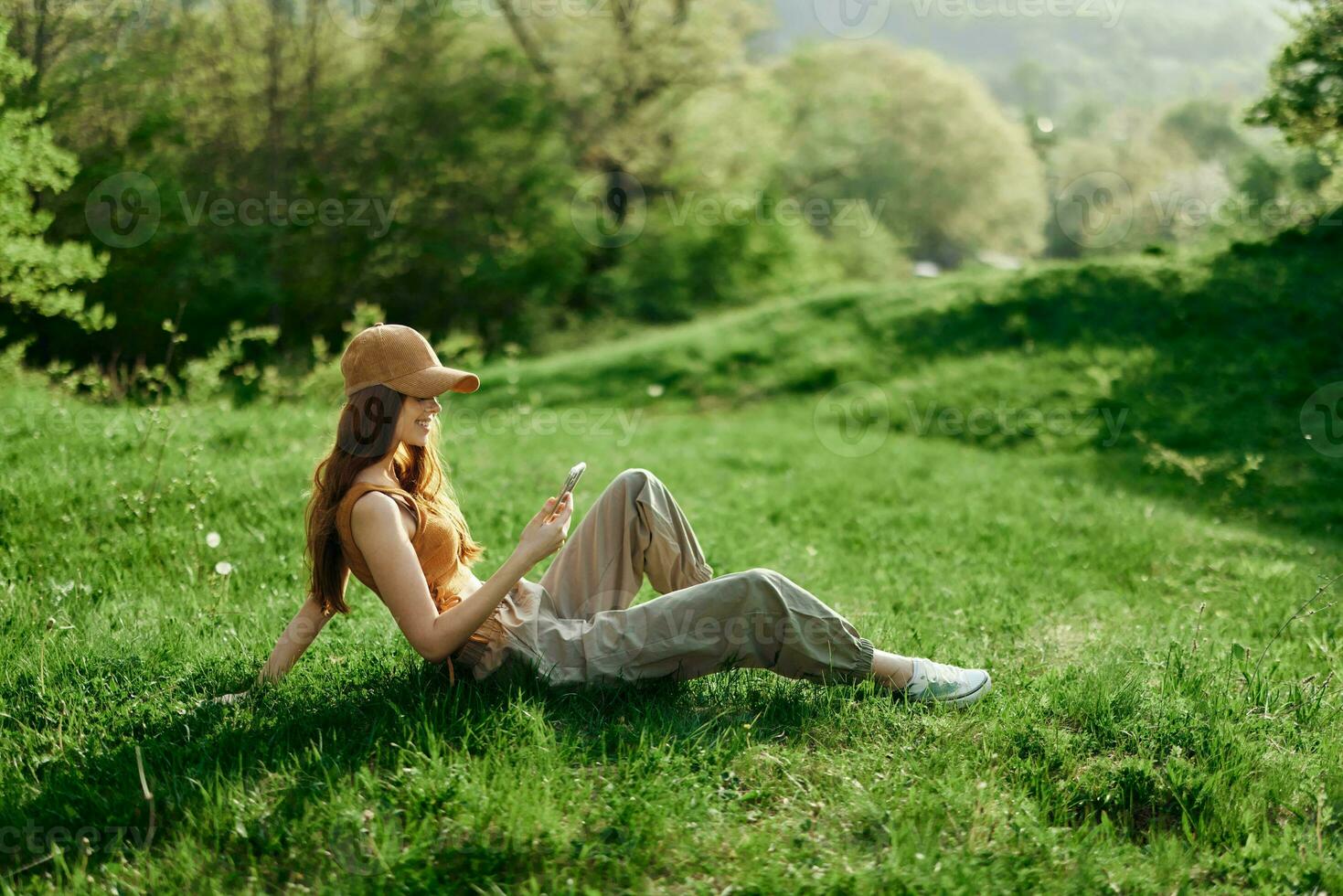 Freelance woman working on her phone against a green summer landscape, the lifestyle of a blogger photo