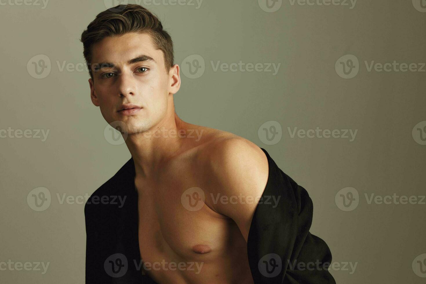 Attractive gentleman with naked shoulders on a beige background with an unbuttoned model jacket photo