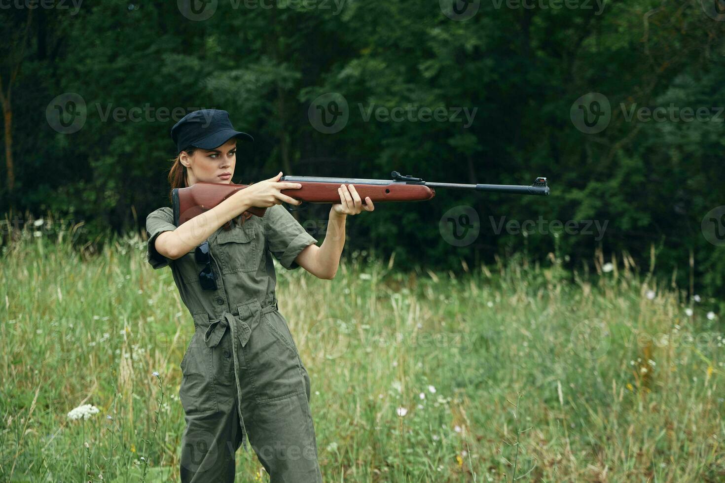 mujer con un arma en mano, un caza verde mono es puntería Fresco aire foto